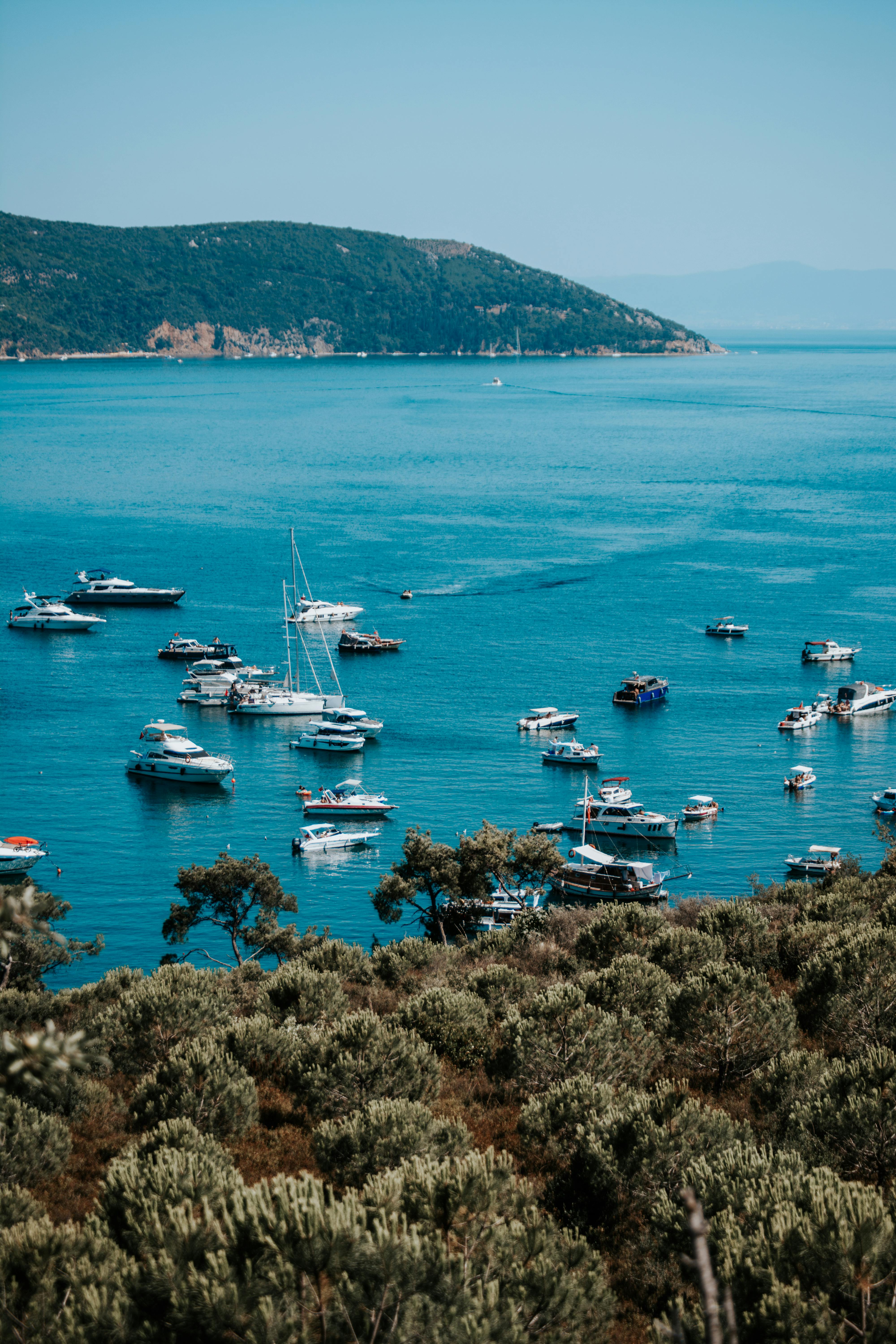 A stunning aerial view of boats moored in a tranquil Mediterranean bay surrounded by lush greenery.