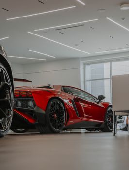A luxurious red Lamborghini Aventador showcased in a modern car showroom setting.