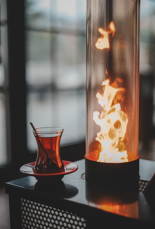 Tea in Glass Next to Lamp with Flame Inside