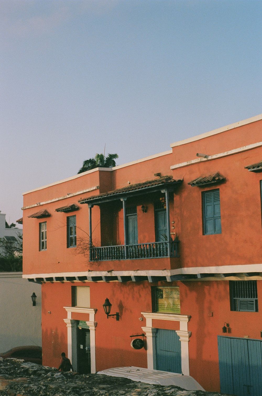 Edificio colonial color coral con balcón azul bajo luz dorada del atardecer