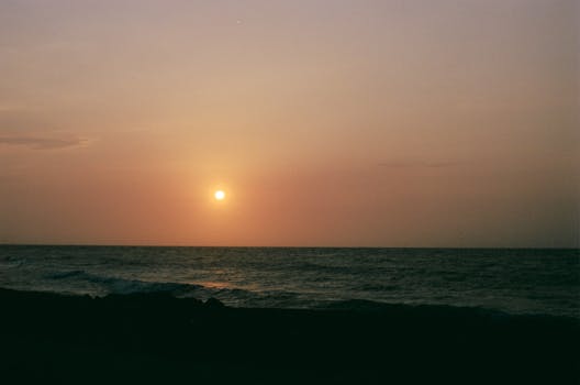 Beautiful sunset over the ocean in Cartagena, Colombia, with warm colors and calm waves.