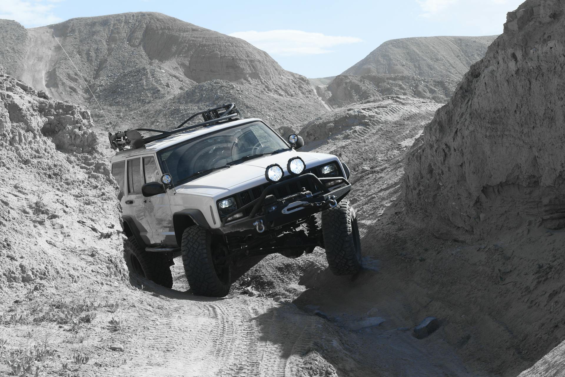 White Jeep Cherokee with Suspension Lift Crossing Rough Rocky Terrain