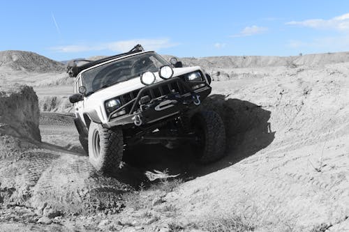 Desaturated Shot of a White Jeep Cherokee Driving through Rough Terrain