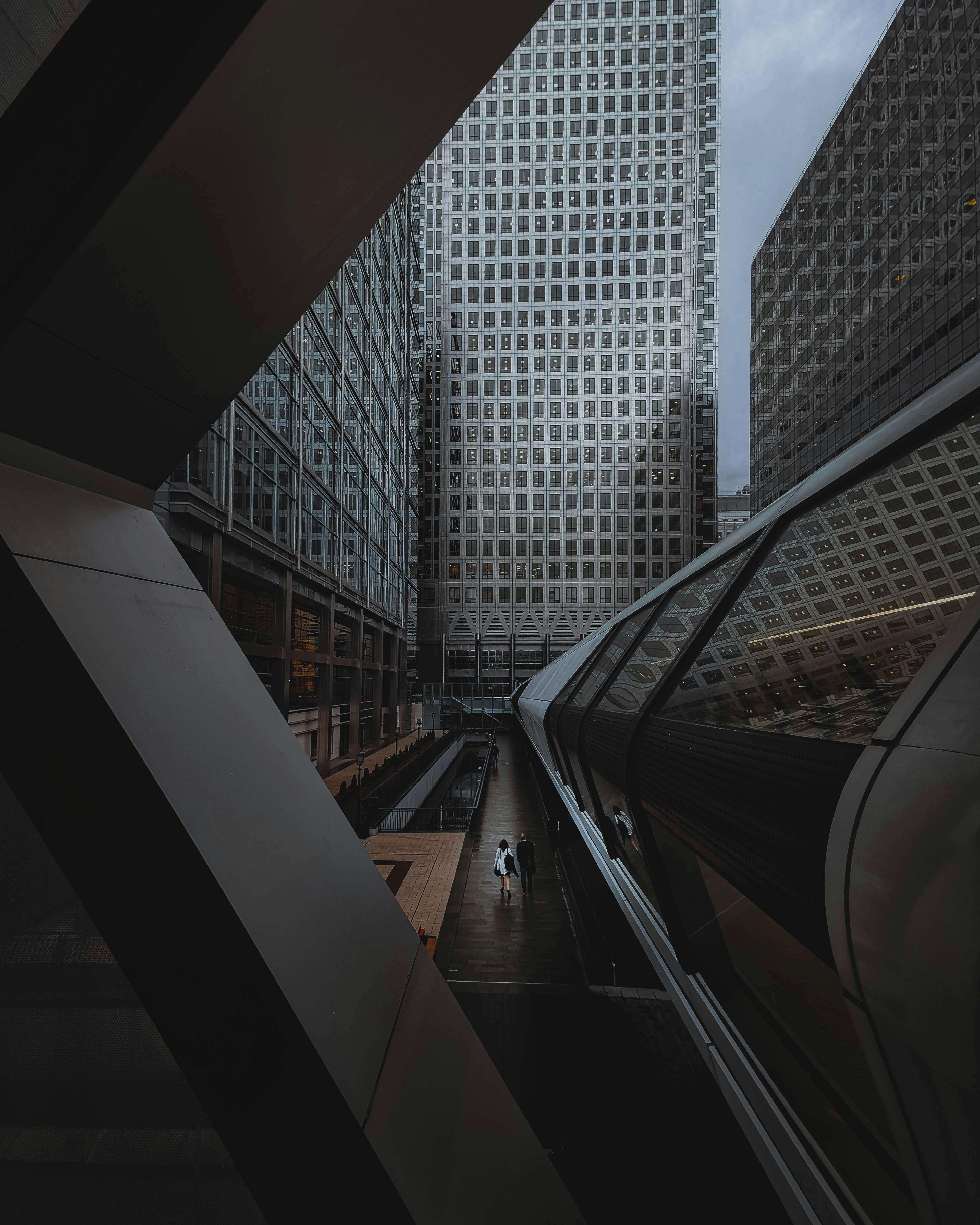 Dramatic view of modern skyscrapers in London's financial district with people walking.