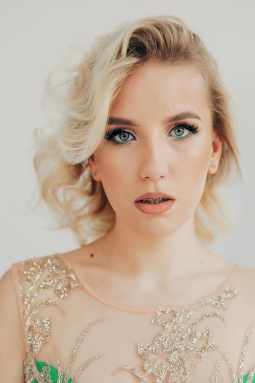 Young Blonde Woman with Teeth Brace Jewelry Posing in Elegant Applique Dress