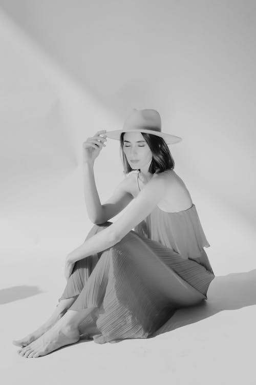 Brunette Woman with Hat in Dress Sitting on Floor