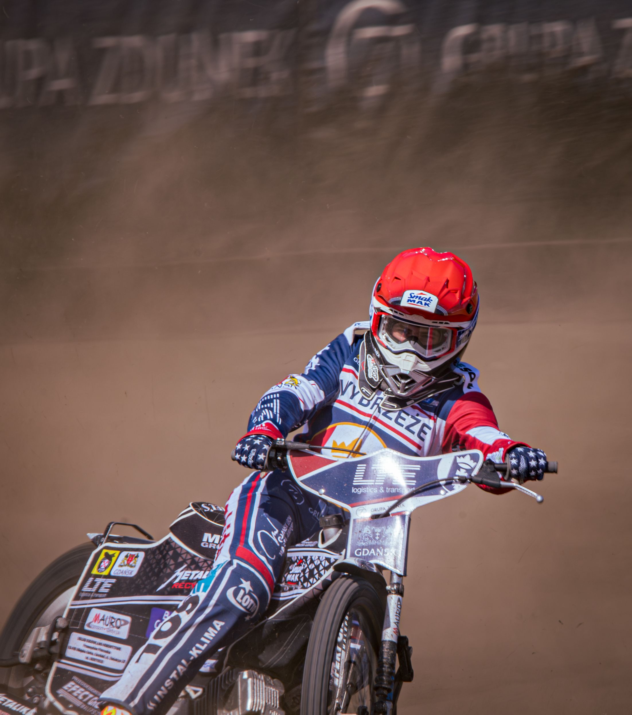 Motorcycle racer speeds through a dusty track, showcasing skill and determination.