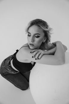 A graceful black and white portrait of a stylish woman in a studio setting, exuding elegance and sophistication.