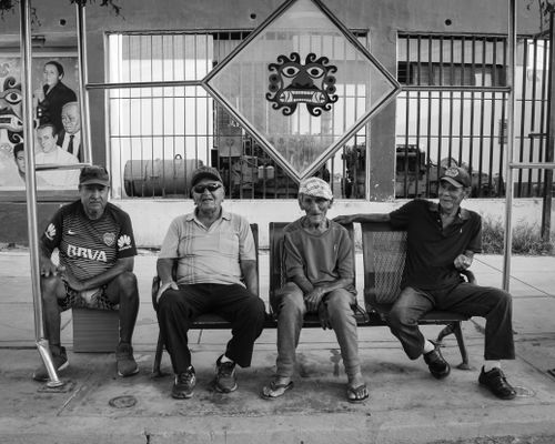 Free Black and white photo of senior men relaxing at a bus stop in Moche, Peru, showing a slice of local life. Stock Photo