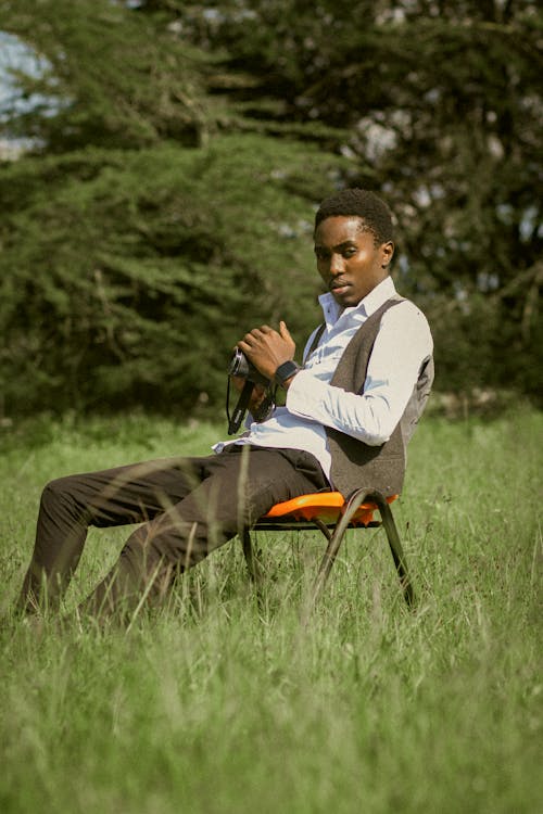 Man Sitting on Chair on Grassland