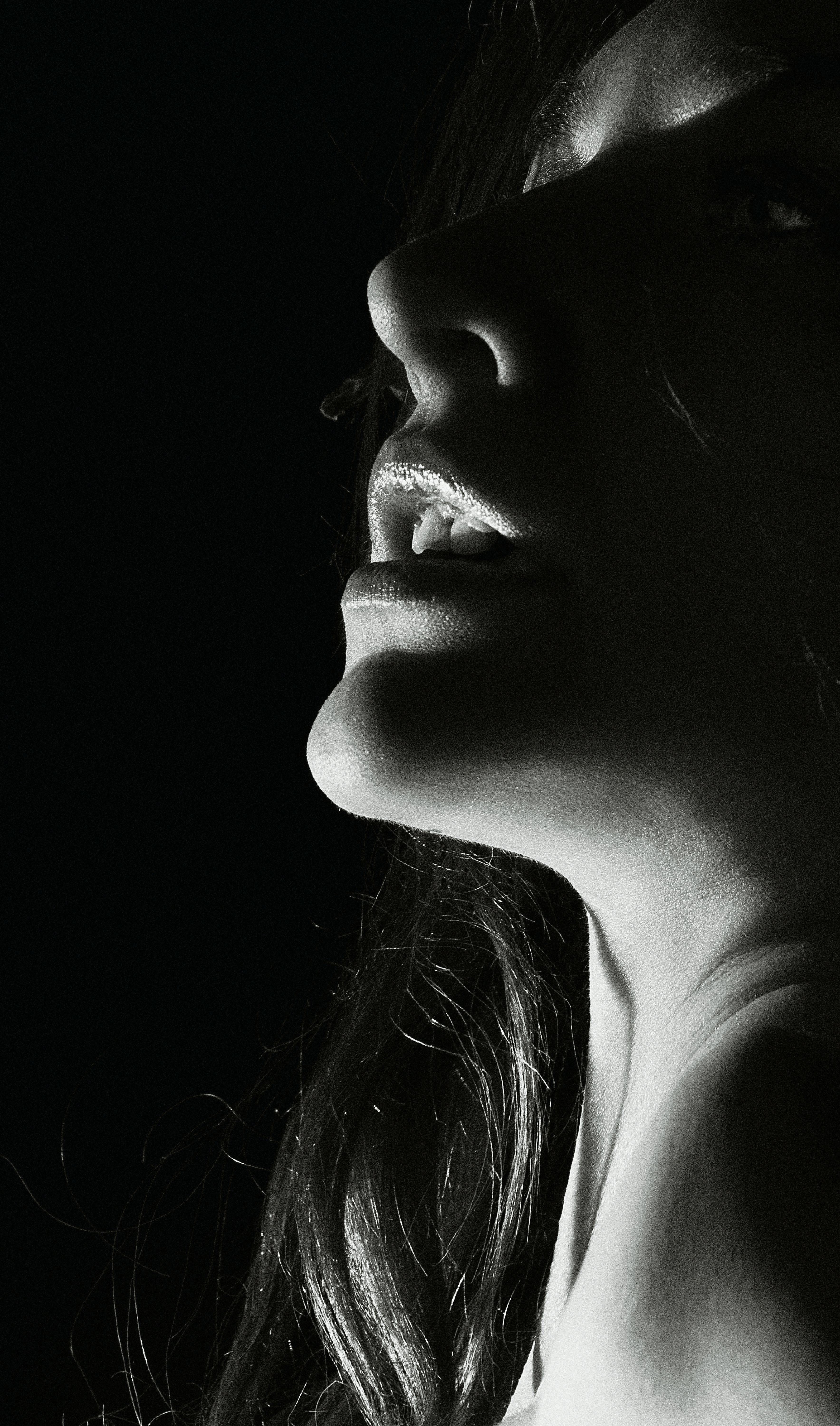 Artistic black and white portrait of a woman's face in low key lighting, highlighting dramatic features.