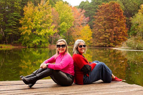 Women Sitting on Wooden Pier in Autumn and Posing