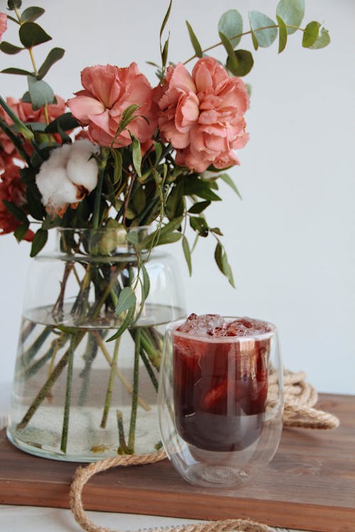 Free Beverage with Ice near Vase with Flowers Stock Photo