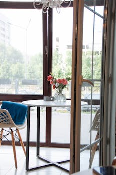 A modern enclosed terrace featuring stylish furniture and a view of urban greenery.