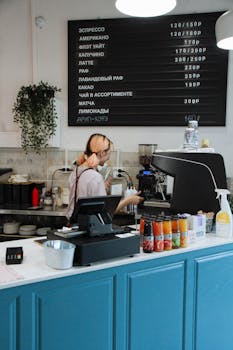 A barista prepares drinks behind the counter in a modern coffee shop.