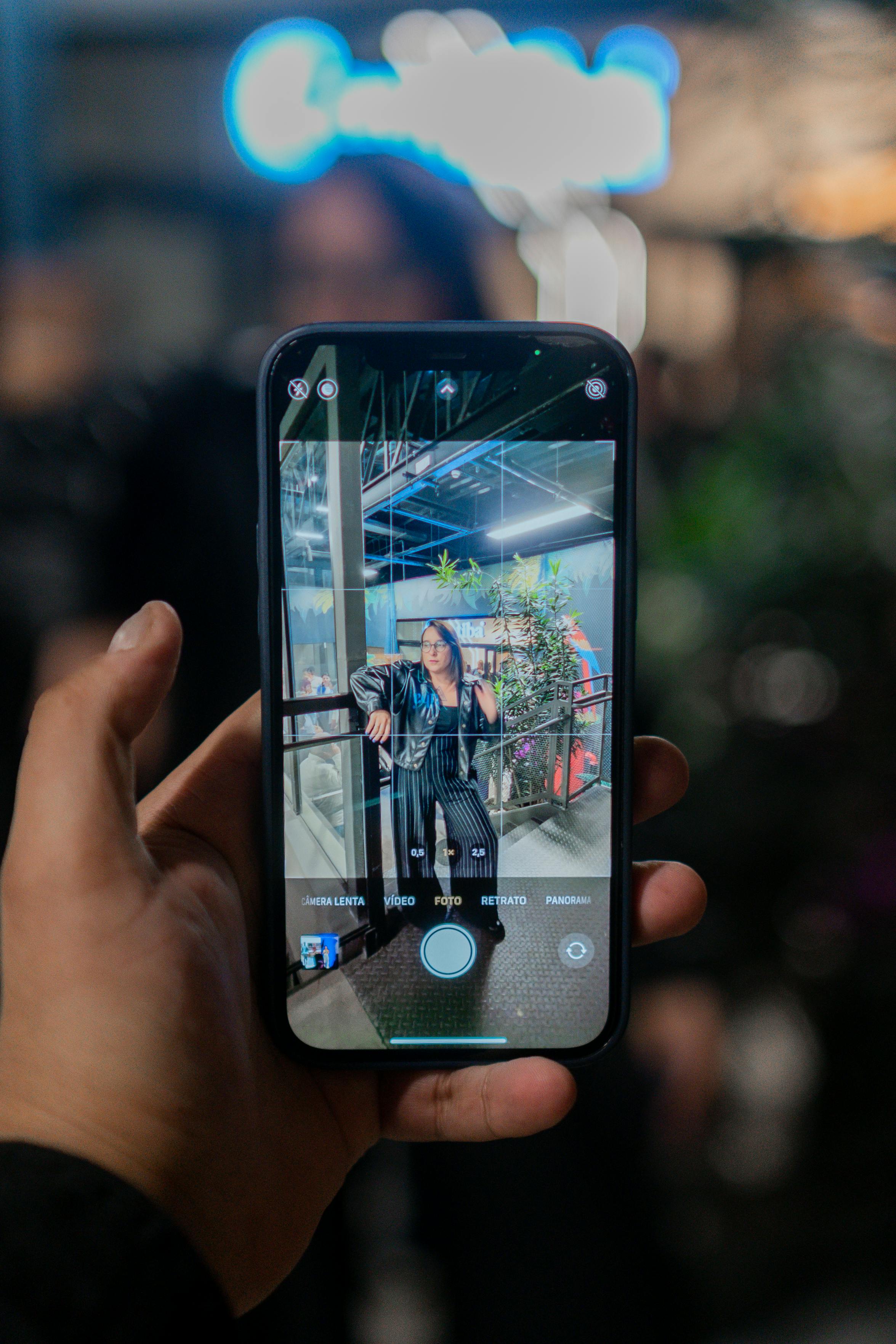 A person captures a portrait with a smartphone in an indoor setting, showcasing reflective technology.