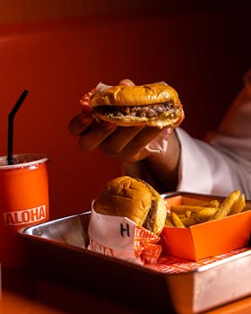 Close-up of a burger, fries, and soda served on a tray in a cozy setting.
