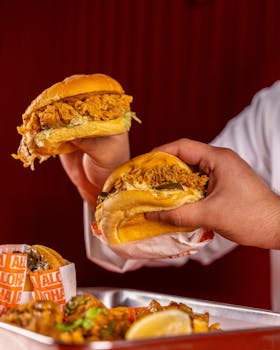 A mouth-watering presentation of fried chicken sandwiches held by hands, ideal for fast food promotions.