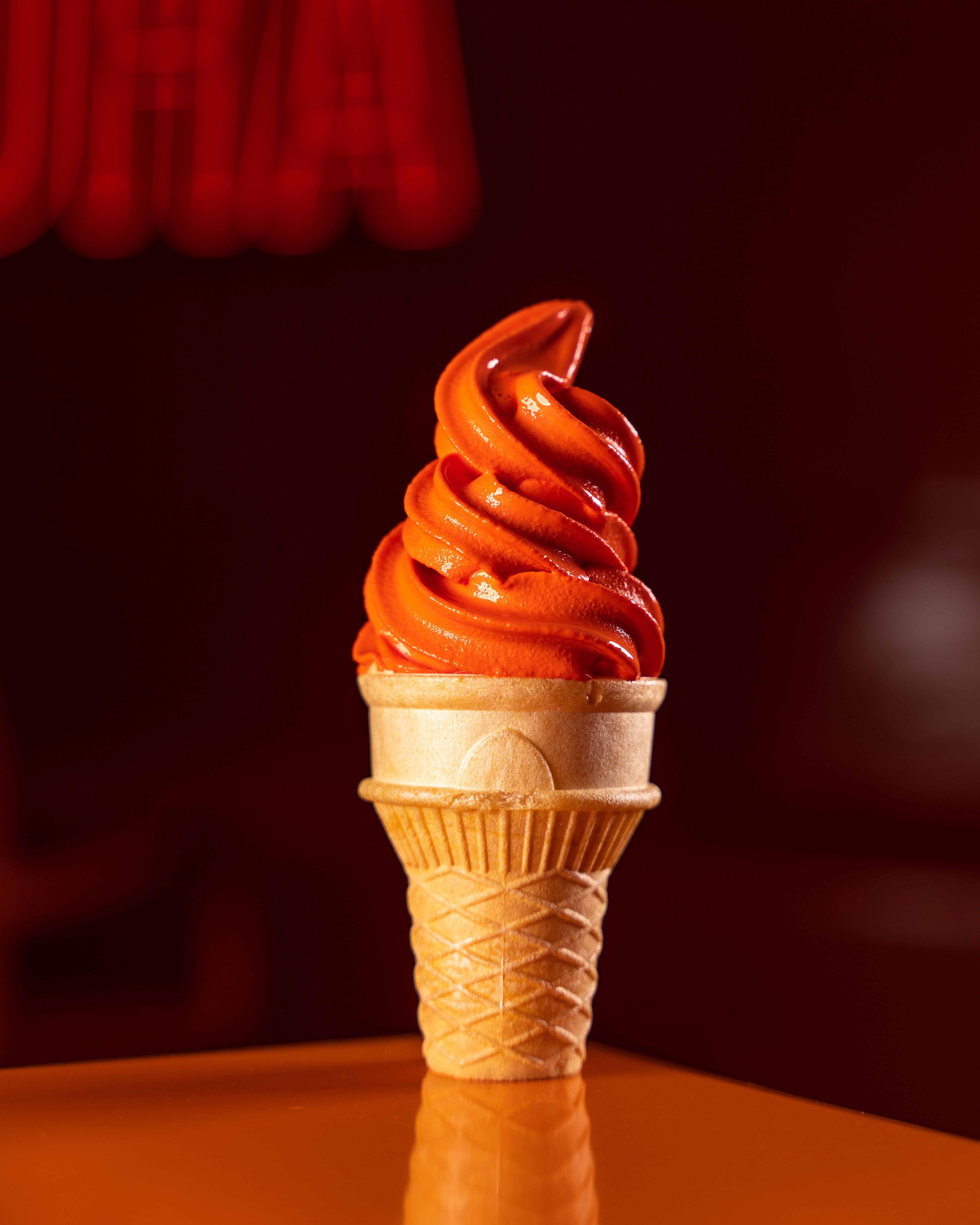 A bright orange frozen swirl piled high on a cone.