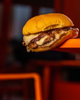 Close-up of a delicious cheeseburger with melted cheese on a vibrant background.