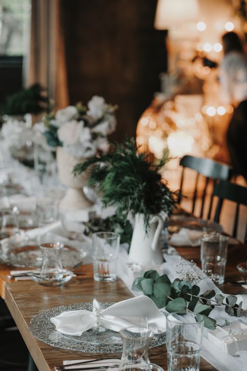 Free A beautifully set wedding table with elegant floral arrangements and luxurious tableware in a warm indoor setting. Stock Photo