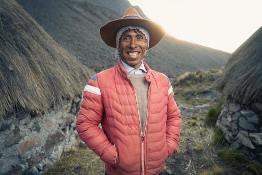 Portrait of a smiling man in a red jacket and traditional hat in the mountains of Cusco, Peru.