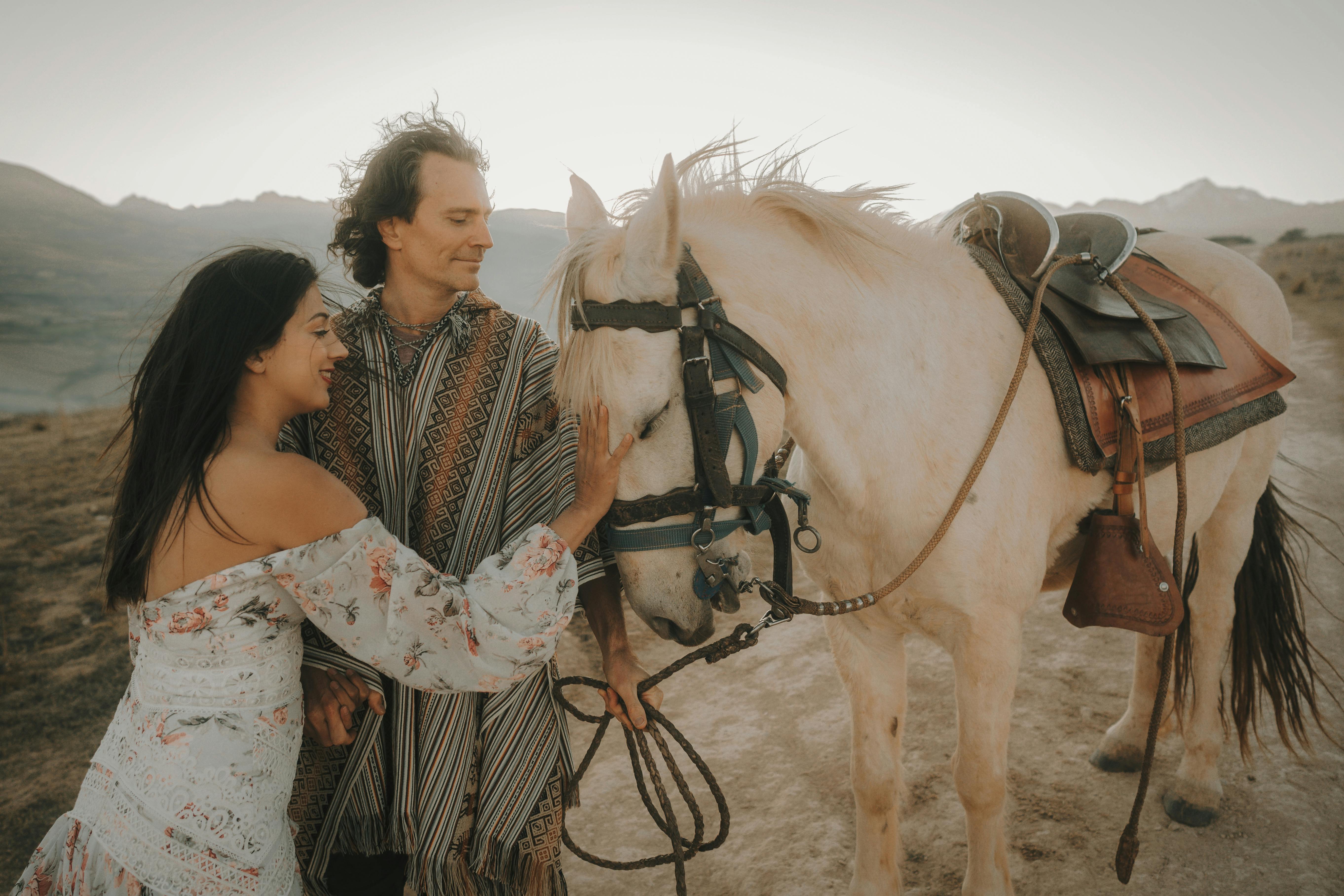 A couple enjoying a serene moment with a horse in a beautiful outdoor setting.