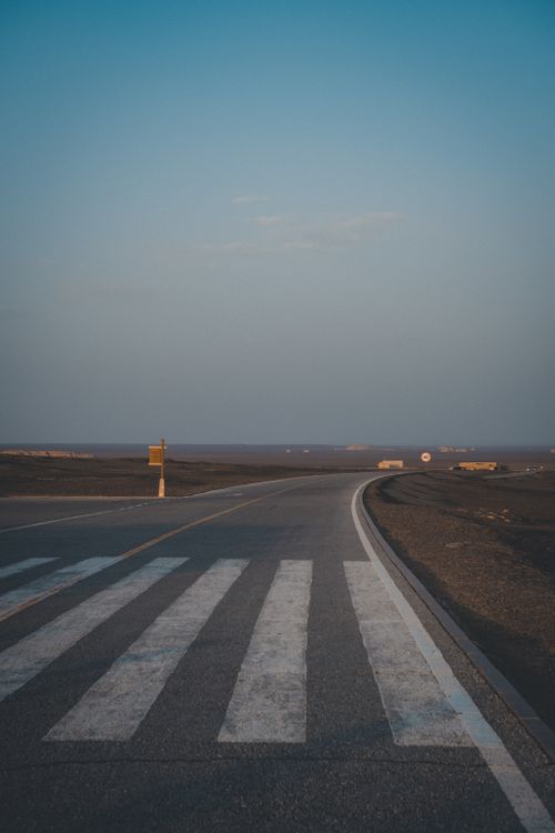 Free Empty rural road with crosswalk during sunrise, offering a serene countryside view. Stock Photo