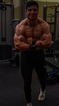 Strong man flexing his biceps in a gym, showcasing muscular build and fitness dedication.