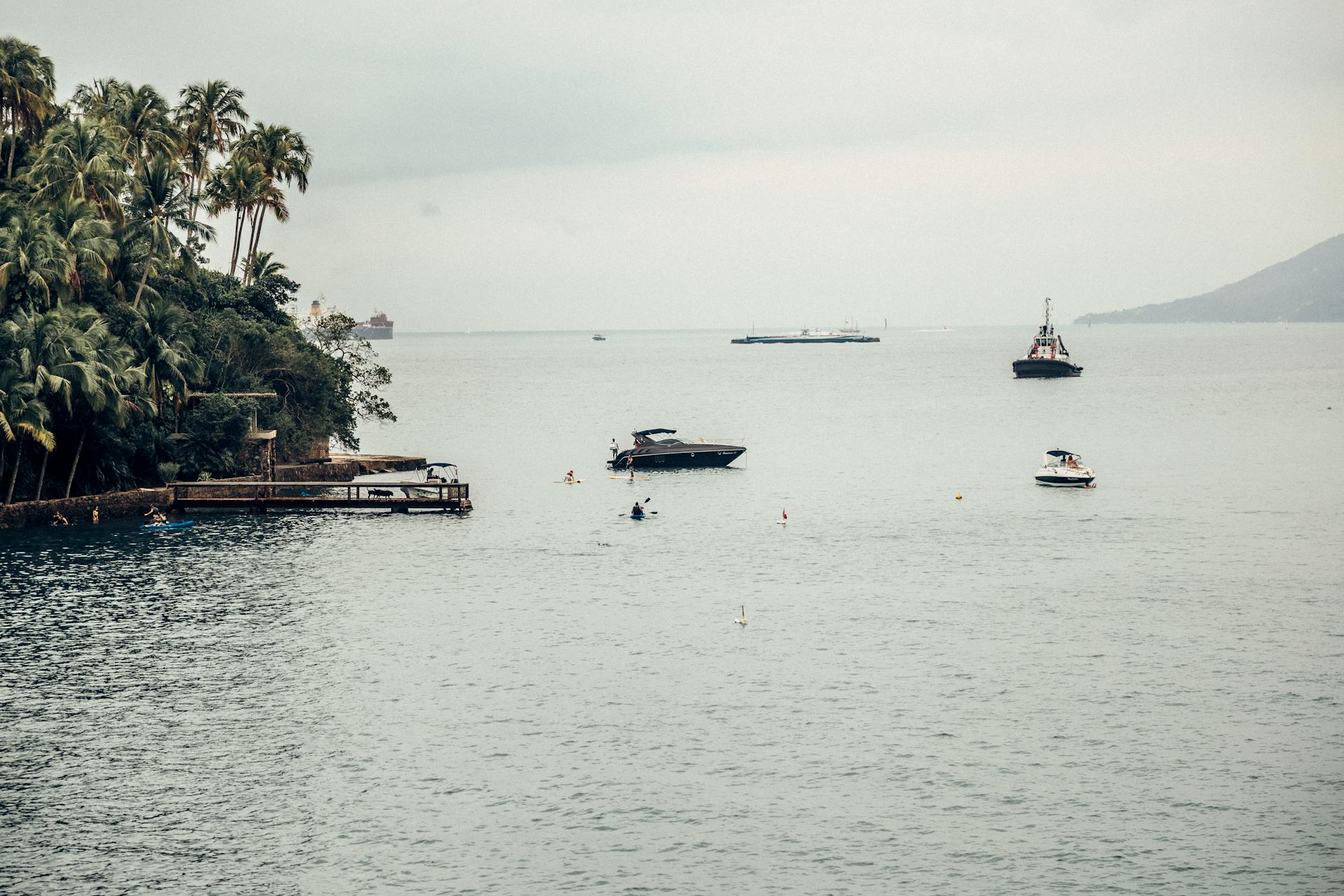 Tranquil scene of boats near tropical island with lush palm trees.