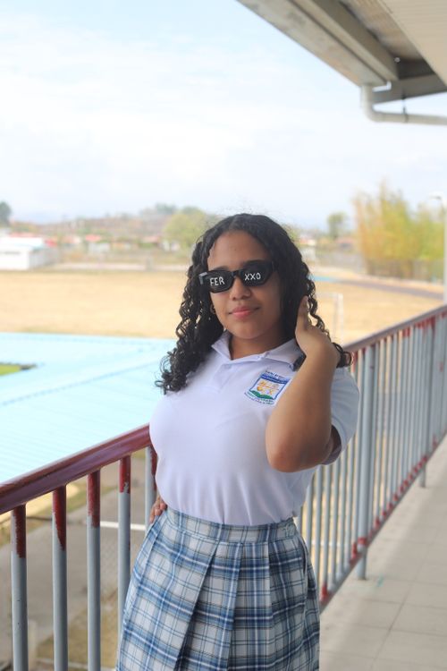 Free A young woman in sunglasses and a Polo T-shirt stands confidently on a balcony. Stock Photo