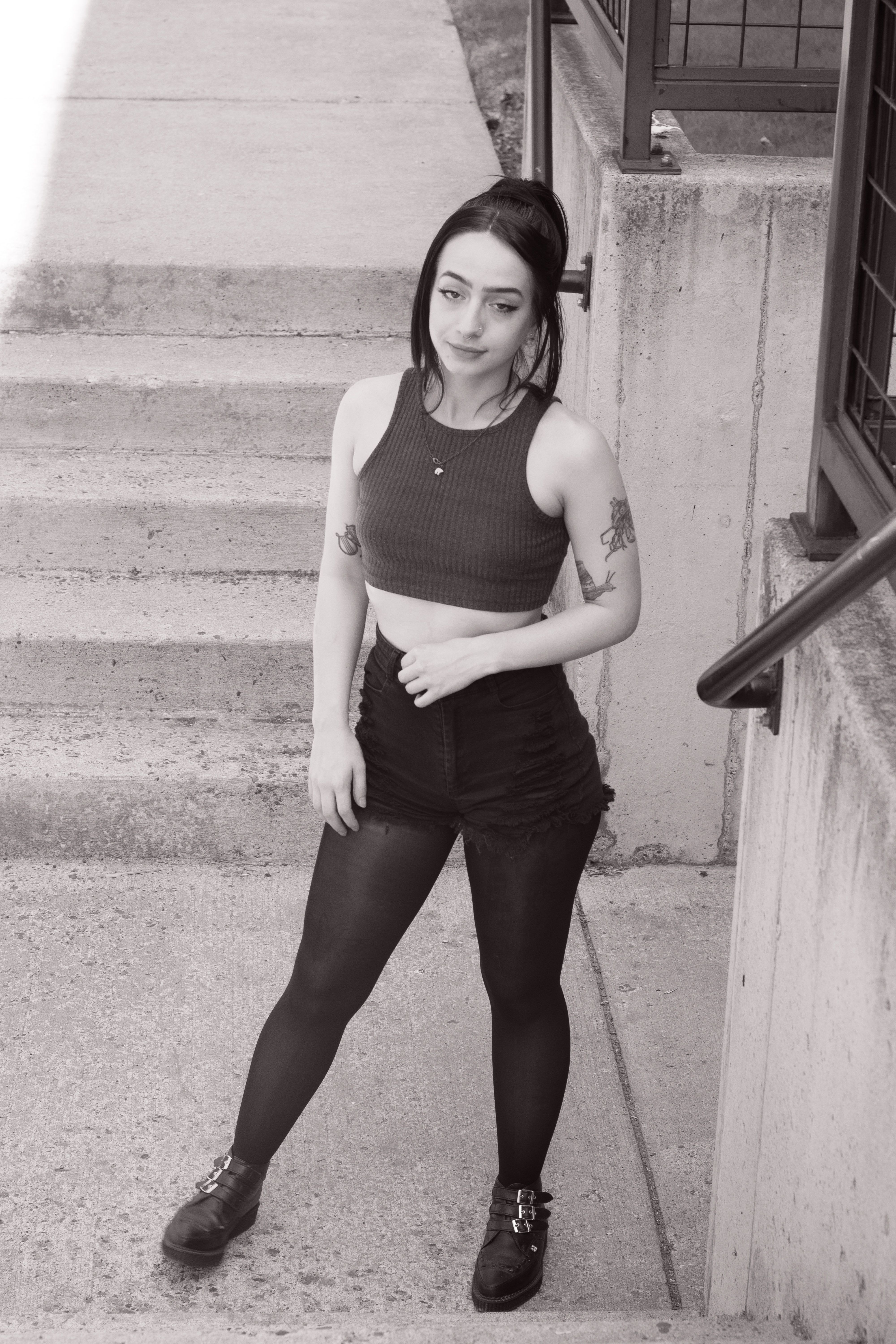 Black and white portrait of a woman posing fashionably on an urban staircase.