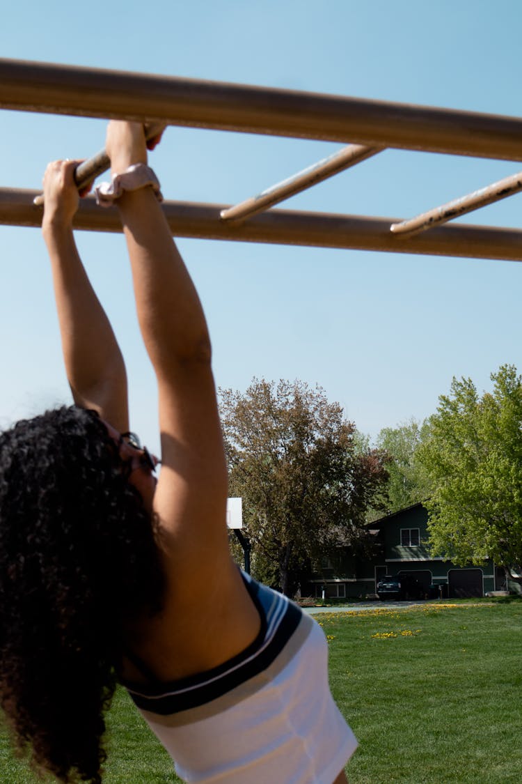 Young Brunette Woman Exercising On A Horizontal Ladder At An Outdoor Gym