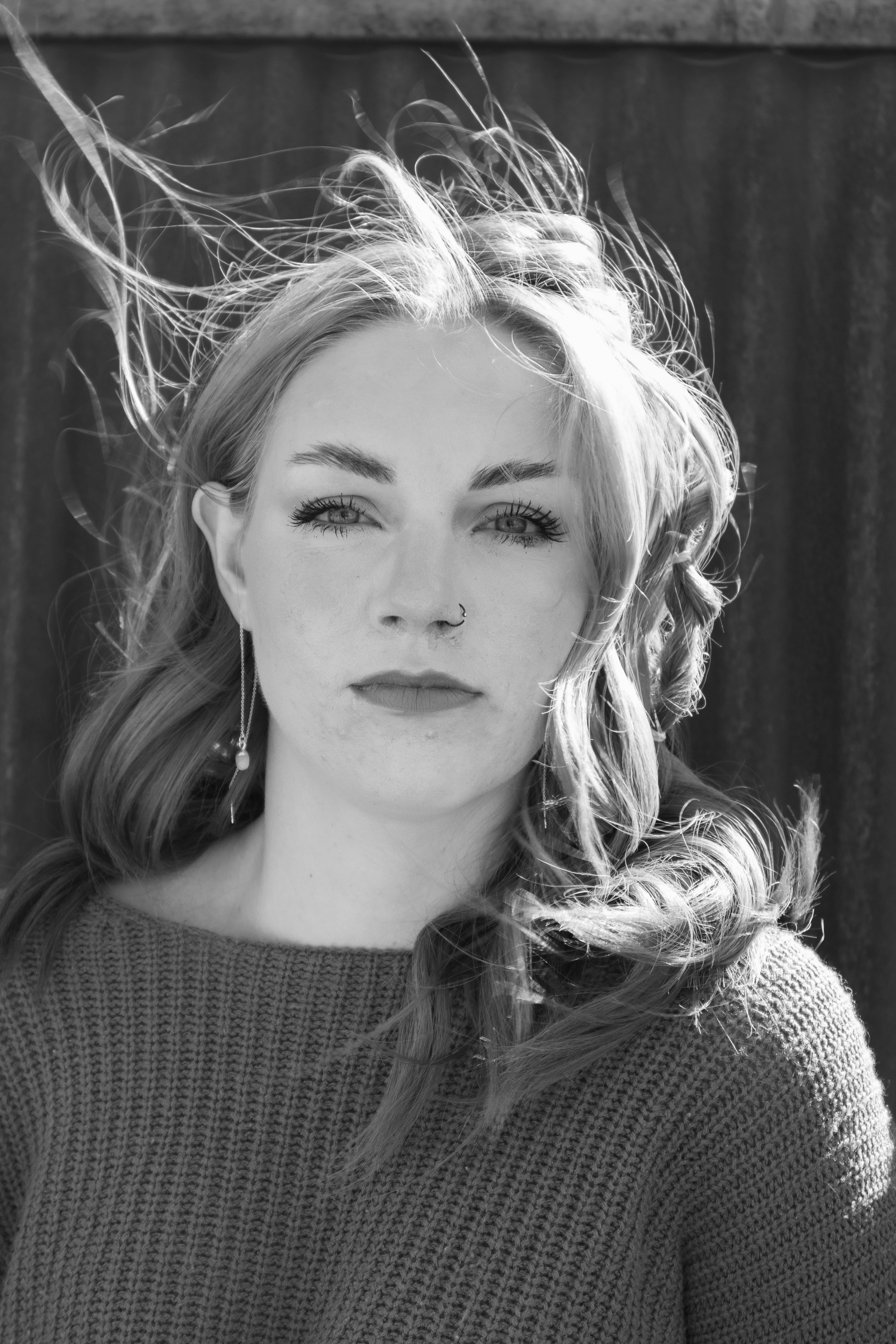 Dramatic black and white portrait capturing a woman with tousled hair and a sweater.