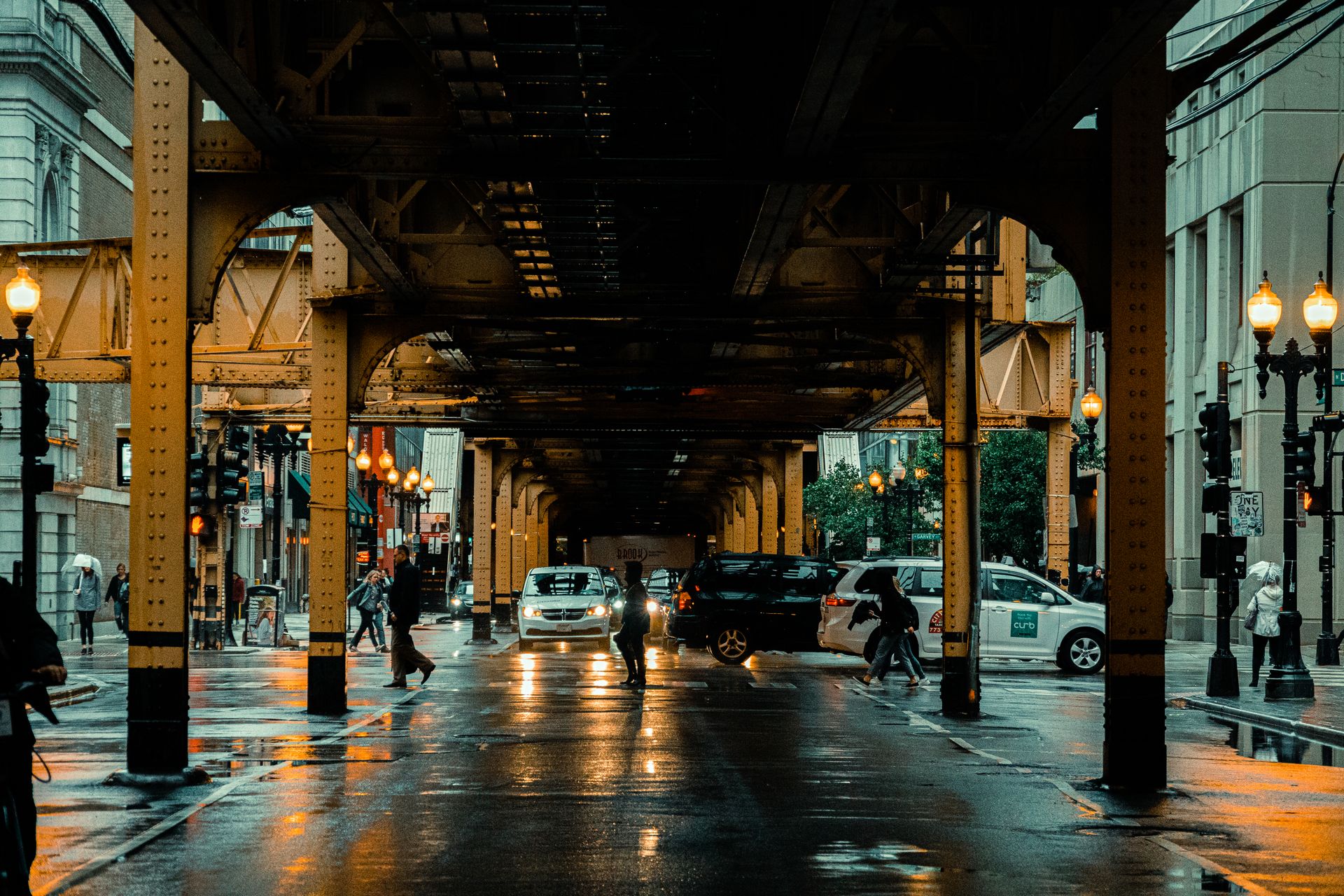 A bustling evening street scene under the famous Chicago L tracks, capturing the urban hustle.