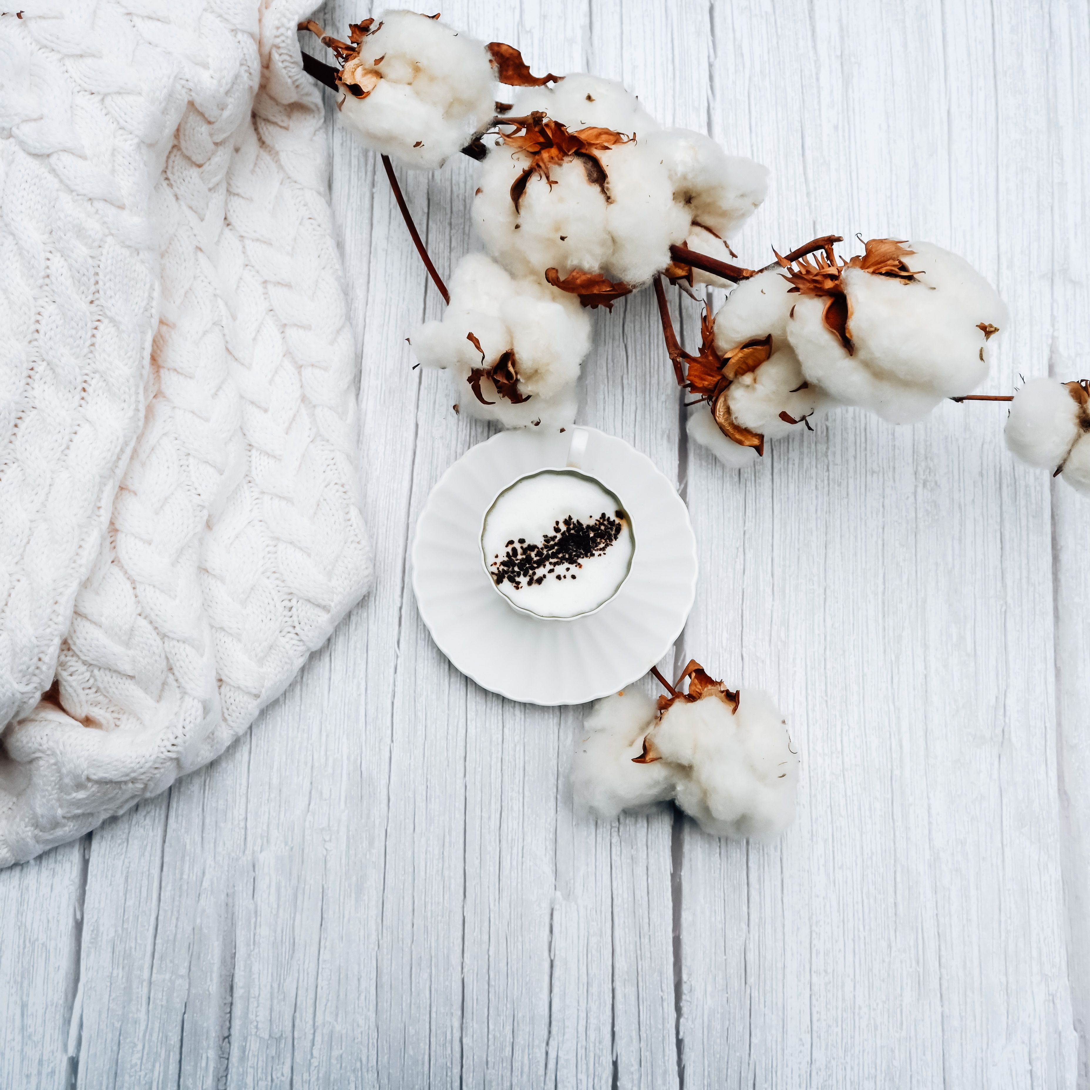 Cream knit garment folded on pale wood — photo by Studio Naae on Pexels