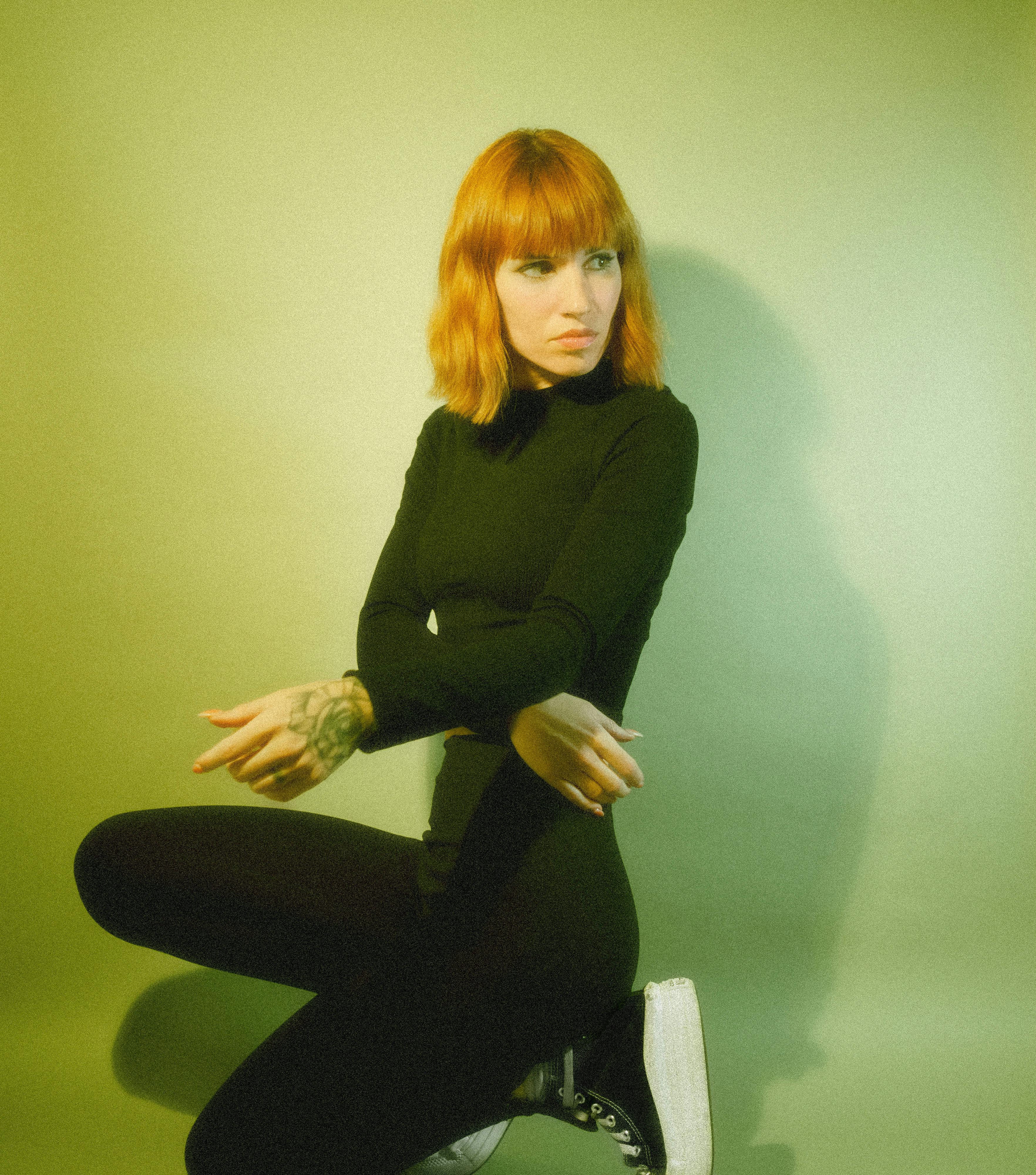 a woman with red hair and black shoes sitting on the ground