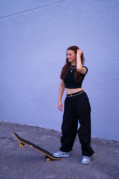 Standing Woman Holding Hand on Skateboard