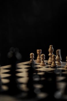 Close-up of a chessboard with wooden pieces against a dark background.
