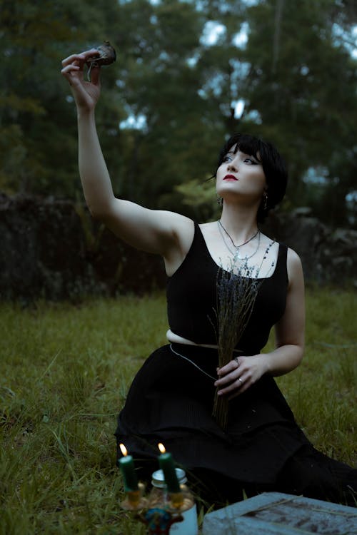 Woman in Black Dress Sitting and Holding Plant