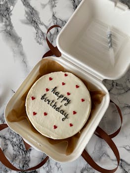 Top view of a birthday cake with red hearts in a sustainable box, perfect for celebrations.