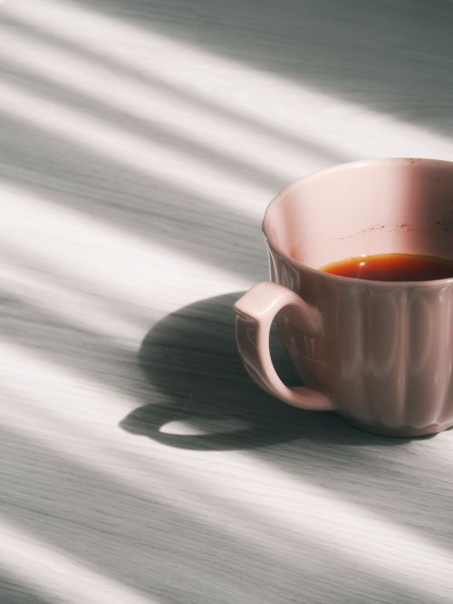 Free A pink coffee cup with shadowed light casting patterns on a surface. Stock Photo