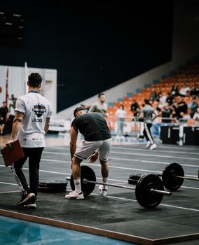 Men in a gym preparing weights for a competitive weightlifting event, showcasing teamwork and strength.