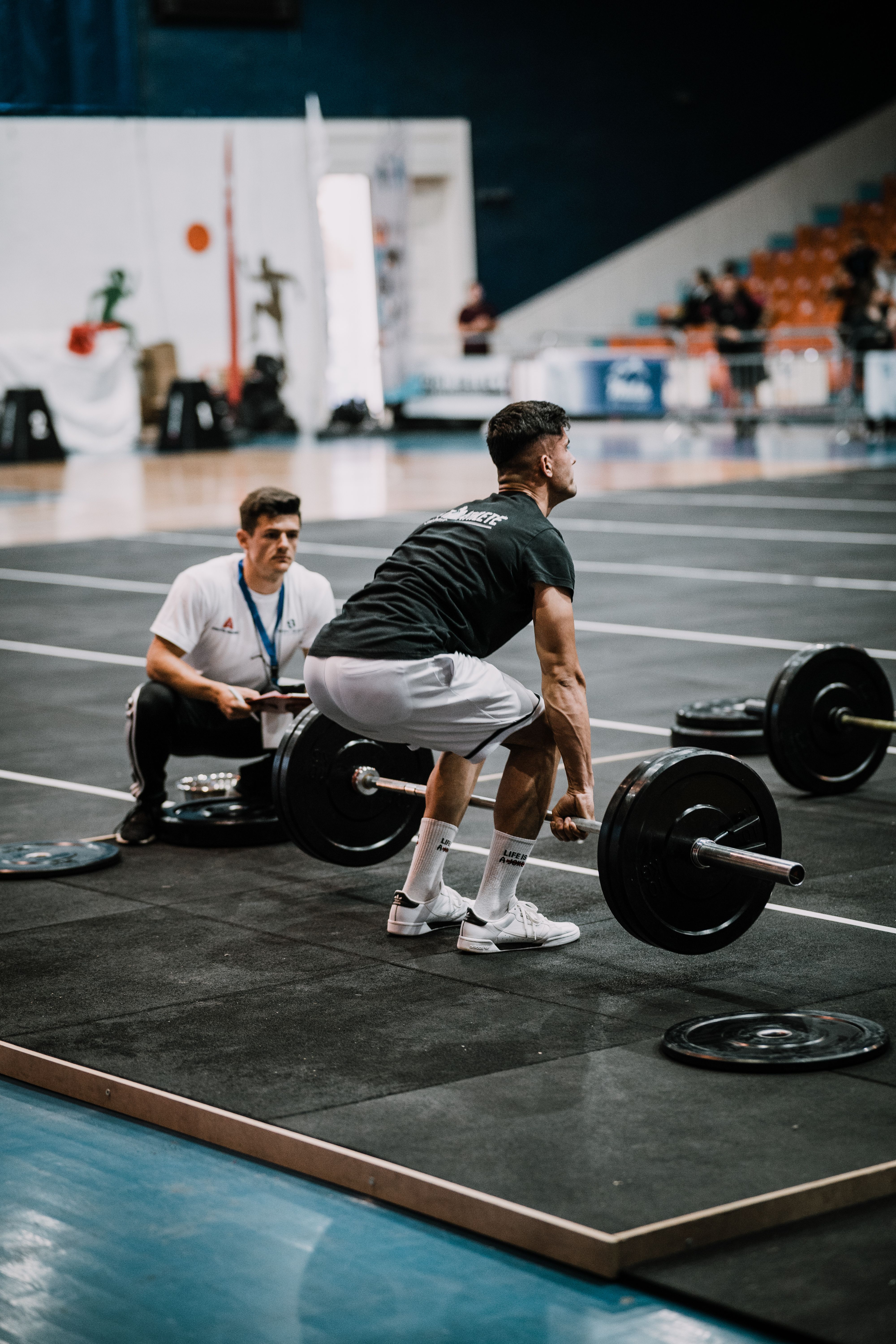 Man performing deadlift during weightlifting competition at the gym, showcasing strength and focus.