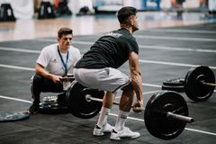 Man performing deadlift during weightlifting competition at the gym, showcasing strength and focus.