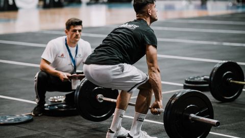 Man performing deadlift during weightlifting competition at the gym, showcasing strength and focus.