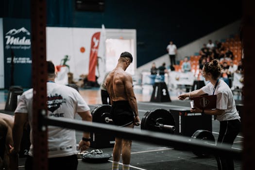 A weightlifting athlete prepares for a lift during a competition with judges observing.