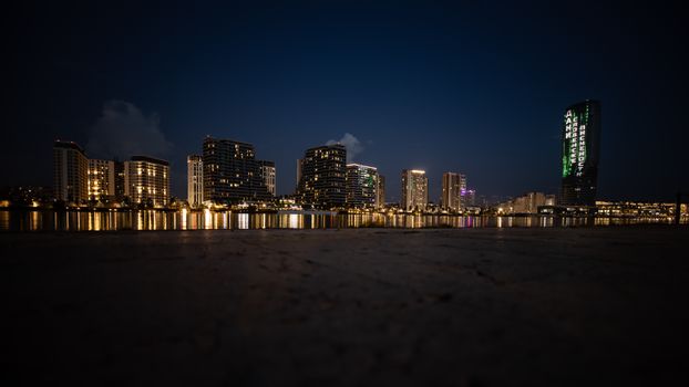 Stunning night view of illuminated skyscrapers reflecting on water, showcasing urban beauty.