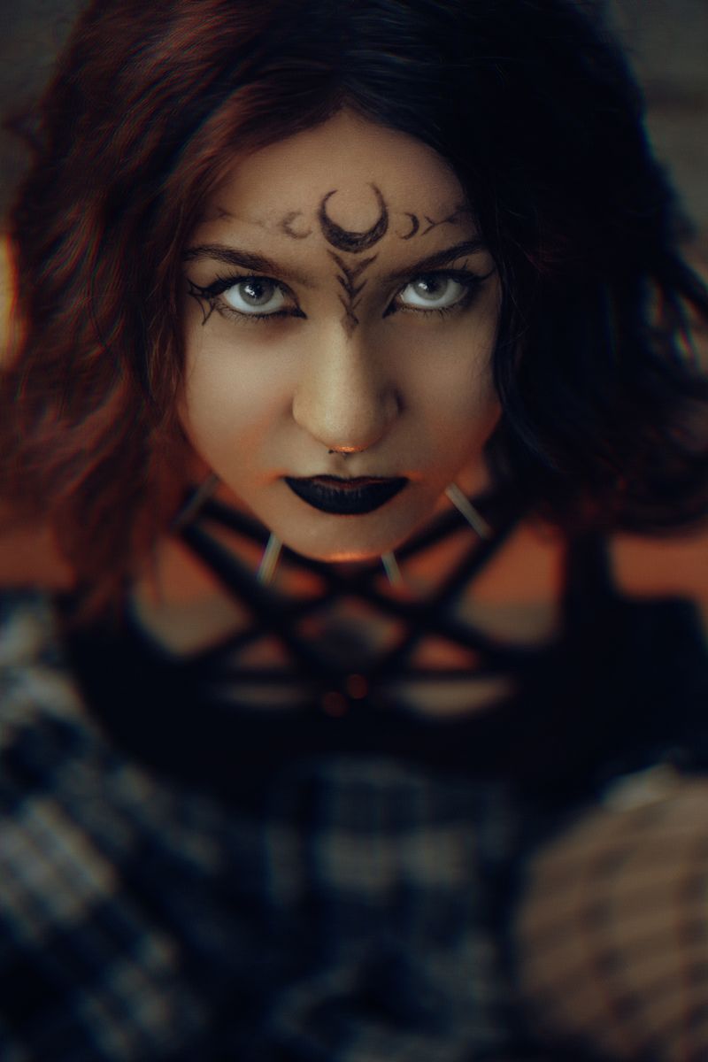 Captivating portrait of a woman with gothic makeup and moon forehead design.