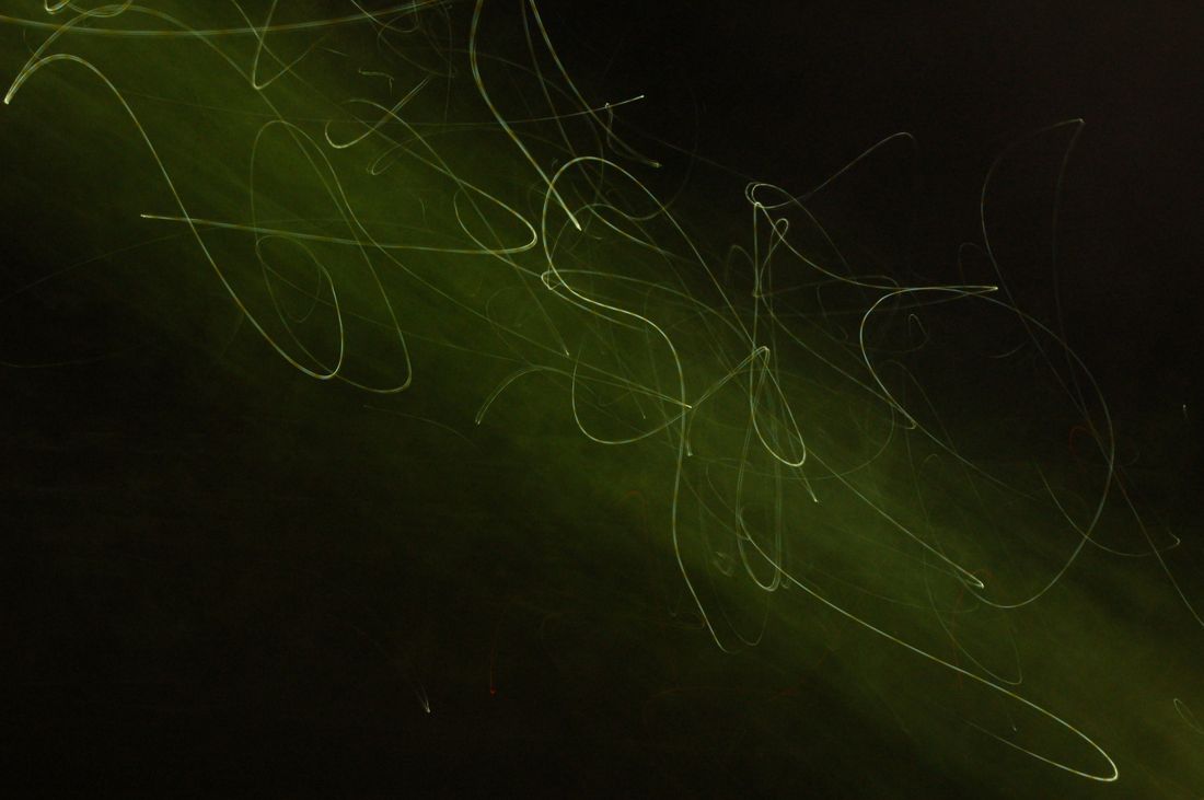 Green light trails curving across a dark field — photo by Philip Haynes on Pexels